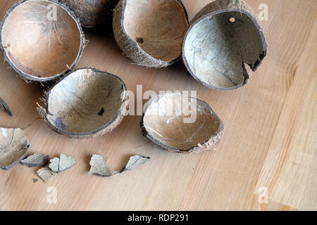 Still life with broken coconut shell ripe white flesh inside and debris on brown wooden table as background. Horizontal close up photo Stock Photo