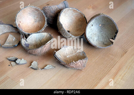 Still life with broken coconut shell ripe white flesh inside and debris on brown wooden table as background. Horizontal close up photo Stock Photo