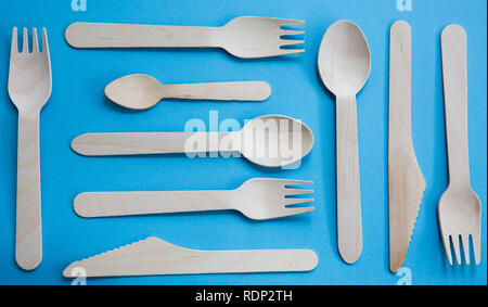 A variety of recyclable wooden cutlery that are disposable and environmentally friendly including knife, fork and spoon on a blue background Stock Photo
