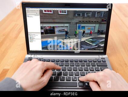 Person sitting at a computer working with Google Street View, screen showing a detailed image of part of the city centre of Stock Photo