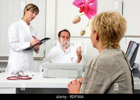 Medical practice, doctor talking to a patient and a medical technician, discussing an examination Stock Photo