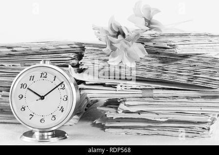 Old mechanical clock and pile of the paper postal mails, black and white Stock Photo