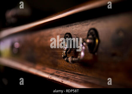 Antique wood table with antique drawer handle in the background and antique chair in the foreground. Stock Photo