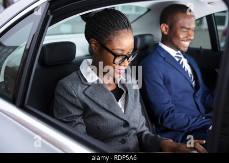 Close-up Of Two Smiling African Businesspeople Traveling By Car Stock Photo