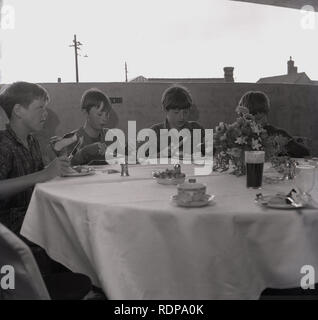 1967, historical, four young boys having a fancy tea on a cloth-covered table in an unusual place....  the top floor of a multi-storey car park, organised by the local council to celebrate its opening, England, UK. Stock Photo