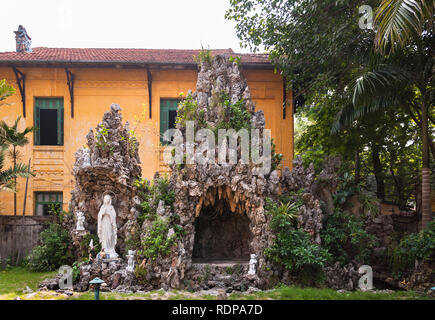 A large shrine made from stone with a statue of the Virgin Mary beside it in the Cua Bac Church grounds, Hanoi, Vietnam Stock Photo