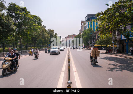 A busy dual carraigeway road with mopeds, motorbikes and cars driving along on a sunny day, Hanoi, Vietnam Stock Photo