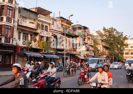 Busy intersection with several cars, mopeds and motorbikes on the road in afternoon light, Hanoi, Vietnam Stock Photo