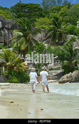 Portrait of happy elderly couple walking on tropical beach Stock Photo
