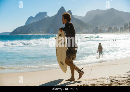 RIO DE JANEIRO - MARCH 20, 2017: Young Brazilian surfers carry their surfboards at the surf break of Arpoador on Ipanema Beach Stock Photo