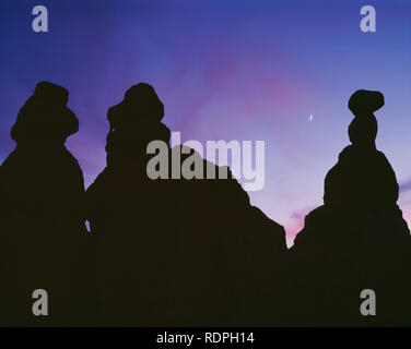 USA, Utah, Bryce Canyon National Park, Crescent moon and sunset colored clouds rise above silhouetted hoodoos in the Queens Garden. Stock Photo