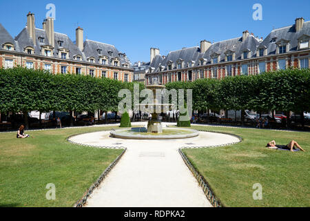 PARIS, FRANCE - JULY 6, 2018: Place des Vosges with people sunbathing on the grass in a sunny summer day, clear blue sky in Paris Stock Photo