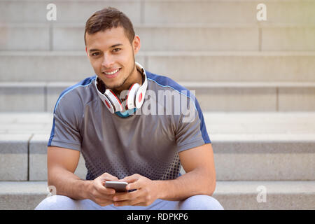 Listening to music young latin man listen headphones smiling copyspace copy space outdoor Stock Photo