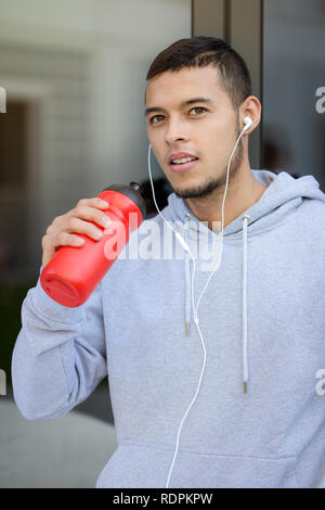 Drinking water young man runner running portrait format jogging sport sports training fitness outdoor Stock Photo