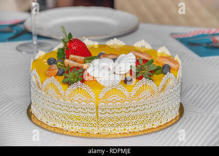 Beautiful delicious yellow cake with fruit and caramel decorations with a smooth jelly surface. Stock Photo