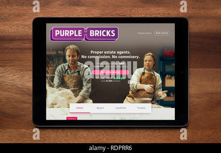 The website of Purple Bricks is seen on an iPad tablet, which is resting on a wooden table (Editorial use only). Stock Photo