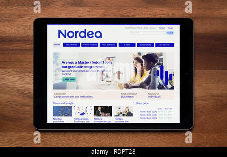 The website of Nordea Bank is seen on an iPad tablet, which is resting on a wooden table (Editorial use only). Stock Photo