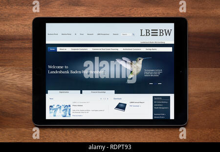 The website of LB BW (Landesbank Baden-Württemberg) is seen on an iPad tablet, which is resting on a wooden table (Editorial use only). Stock Photo