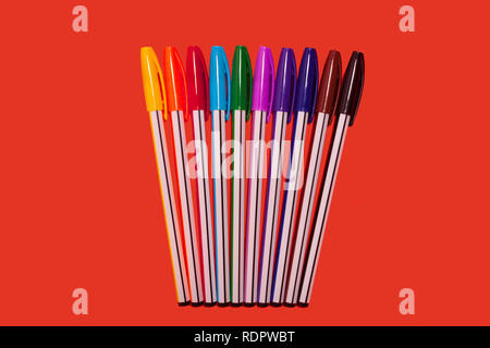 colored pens lying on a red background Stock Photo
