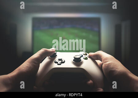 Man is playing on the console. Man holding gamepad and playing soccer game Stock Photo