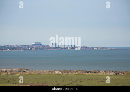 A view across saltmarshes on a hot and hazy day from Warton Crag of Heysham nuclear power station with part of Morecambe in the foreground. Lancashire Stock Photo