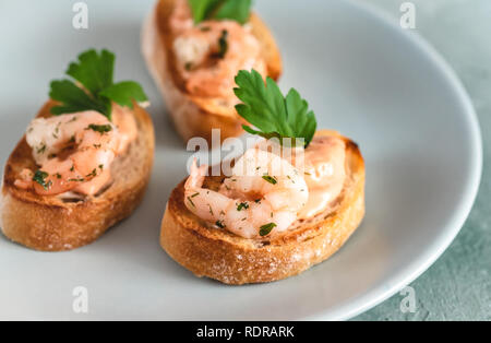 Bruschetta sandwiches with shrimps, creamy sauce and parsley. Stock Photo