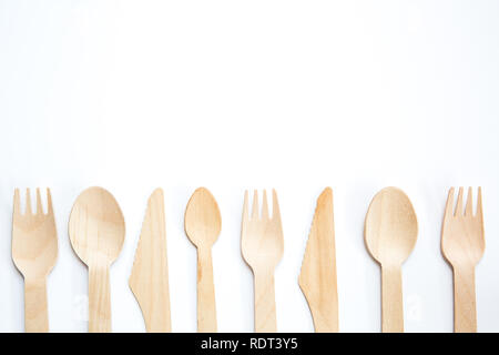 A flat lay of a variety of sustainable and environmentally friendly wooden cutlery including knife, fork and spoon with copy space on white background Stock Photo