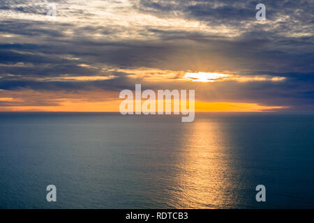 Sun bursting through the clouds, reflected in calm ocean waters, San Simeon, California Stock Photo