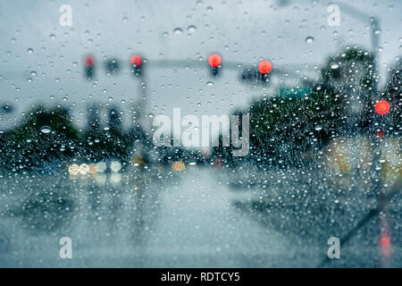 Waiting at a traffic junction for the green light during a rainy day; raindrops on the windshield Stock Photo