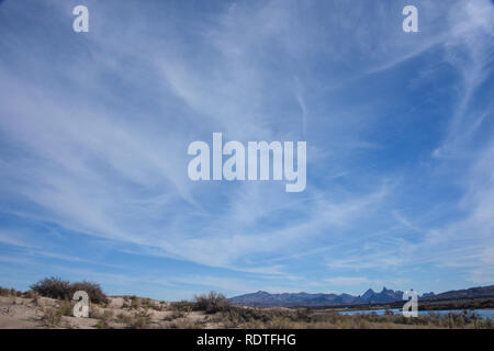 Wispy clouds above the Havasu National Wildlife Refuge on the Colorado River in Arizona wit the Needles Mountains in a sliver on the horizon Stock Photo