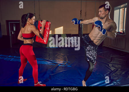 The guy and the girl work out the punches in the gym. Sport and motivation. Stock Photo