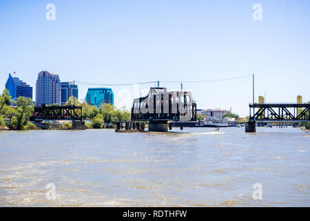 The I Street Bridge is a historic metal truss swing bridge located on I Street in Sacramento; the city's downtown skyline in the background, Californi Stock Photo