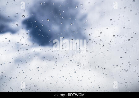 Raindrops on the windshield; in the background white clouds and a spot of blue sky, California Stock Photo