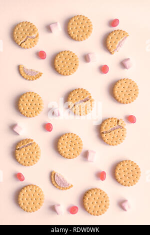 Cookies biscuits crackers candies and marshmallows flat lay on beige background, top view. Stock Photo
