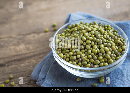 Mung beans in bowl on wooden table, ready to cook, close up. Stock Photo