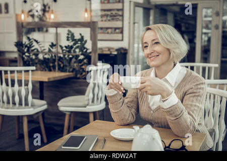 Beautiful mature woman sitting in cafeteria waiting for her husband Stock Photo