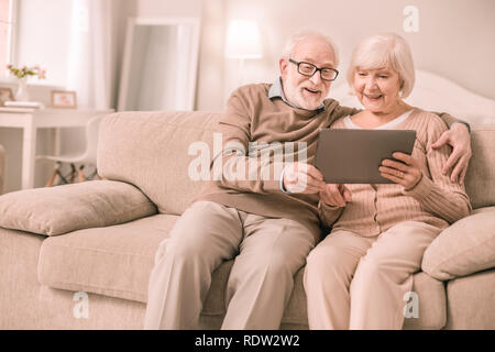 Cheerful pensioners having video conference with children Stock Photo