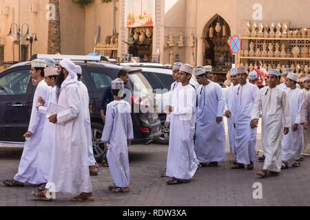 Nizwa, Oman - November 2, 2018: Group of Omani boys in traditional clothes with dishdasha and kuma at Nizwa market Stock Photo