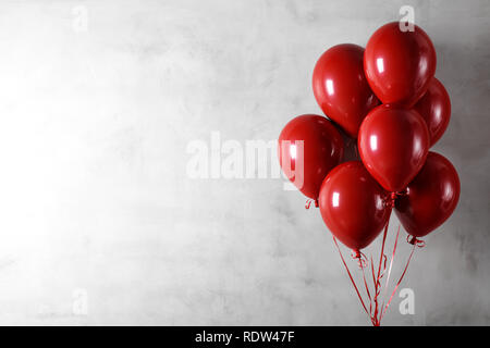 Bunch of red balloons on concrete wall background Stock Photo