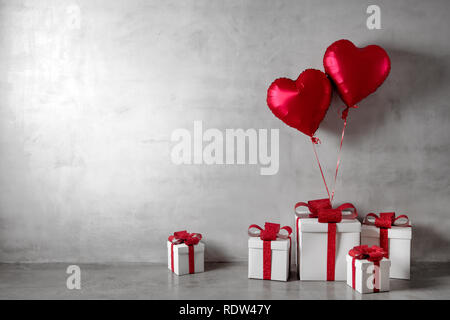 Red balloons and white gift boxes on concrete wall background Stock Photo