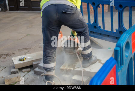 road worker cuts slab of concrete using an angle grinder or circular power saw Stock Photo