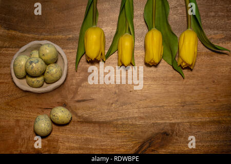Wooden copy space decorated with yellow tulips and Quail eggs  - top view - easter copy-space Stock Photo