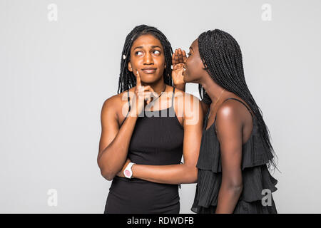 Portrait of two happy young african women sharing secrets isolated Stock Photo