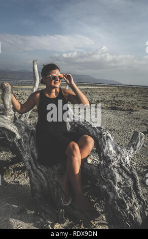 Young Woman posing on the tree on the sandy beach Stock Photo
