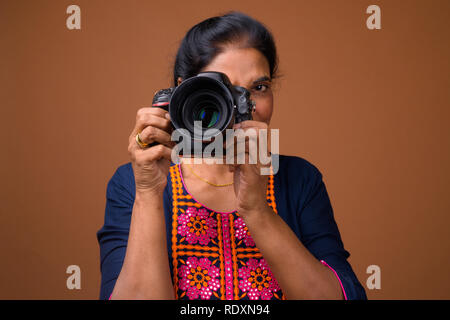 Mature beautiful Indian woman photographer using DSLR camera Stock