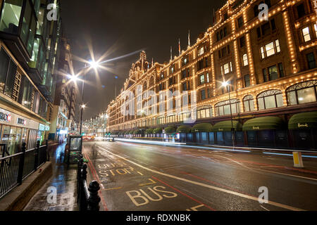 Exterior view of Harrods Department Store in London at night during Winter period. Night traffic street scenery in a typical rainy day in UK Stock Photo