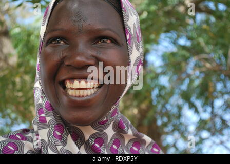 A young Fulani woman in Niger, Africa, caught by the camera while sharing humor with a friend. Stock Photo