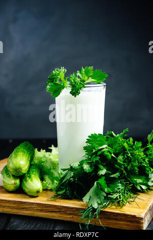 Fresh plain homemade yougurt with cucumber herbs over dark background, probiotic cold fermented dairy drink. Stock Photo