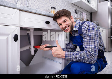 Young Male Plumber Repairing Sink Pipe With Adjustable Wrench Stock Photo