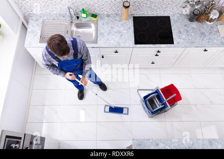 High Angle View Of Janitor Cleaning Floor With Mop In Kitchen Stock Photo